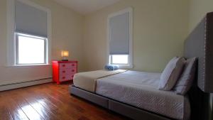 1 dormitorio con 1 cama con cómoda roja y 2 ventanas en El Edén, en Parkchester