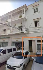 dwa samochody zaparkowane przed białym budynkiem w obiekcie Apartamento centro histórico 303-2 w mieście Cartagena de Indias