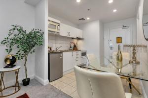 a kitchen with a glass table and white cabinets at Your Family Getaway - Rooftop Spa & Pool! in Auckland