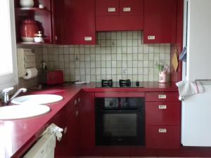 - une cuisine rouge avec des placards rouges et un lave-vaisselle noir dans l'établissement Maison Belz, 3 pièces, 4 personnes - FR-1-397-52, à Belz