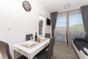 a dining room with a white table and chairs and a window at Apartments Villa LA in Veliki Drvenik