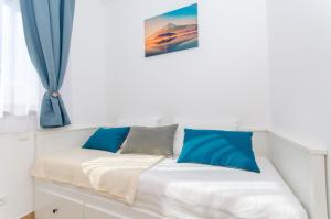 a white bed with blue pillows on top of it at Apartments Villa LA in Veliki Drvenik +84 photos