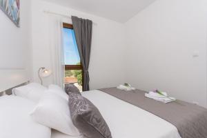1 dormitorio con 2 camas y ventana en Apartments Villa LA, en Veliki Drvenik
