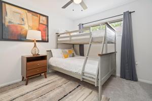 a bedroom with a bunk bed and a night stand with a lamp at The Gated Modern Home Near NRG and Medical Center in Houston