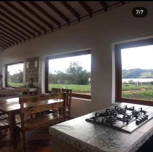 cocina con fogones, mesa y 2 ventanas en Villa Rosario en Aquitania