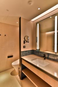 八里區的住宿－八里福朋喜來登酒店，一间带水槽、卫生间和镜子的浴室