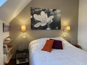 ein Schlafzimmer mit einem weißen Bett und einem Blumengemälde an der Wand in der Unterkunft Appartement Trégastel, 3 pièces, 3 personnes - FR-1-368-380 in Trégastel