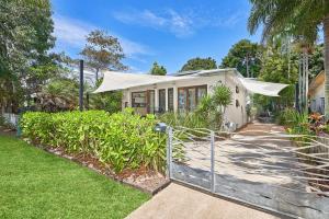 een wit huis met een hek ervoor bij Onda Beach Clifton Beach in Clifton Beach