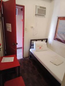 a small room with a bed and a red door at WJV INN Mandaue Centro in Mandaue City