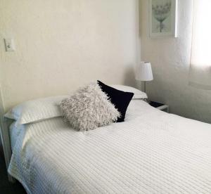 uma cama branca com almofadas pretas e brancas em Kenata-Fairway em Perth