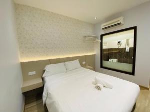 1 dormitorio con cama blanca y espejo en Hotel U and Me, en Kulai
