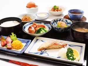einen Tisch mit Teller mit Lebensmitteln und Schüsseln mit Lebensmitteln in der Unterkunft Fukui Hotel in Obihiro
