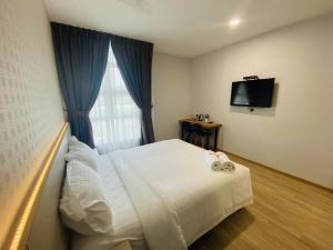 a bedroom with a white bed and a television at Hotel U and Me in Kulai