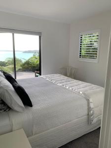 a white bedroom with a large bed and a window at Sea Veiws Kaha Place in Russell