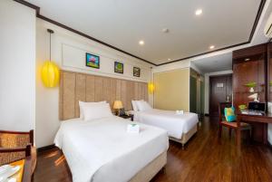 a hotel room with two beds and a desk at Babylon Grand Hotel & Spa in Hanoi