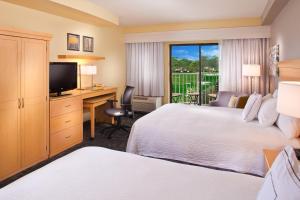 a hotel room with two beds and a desk and a television at Courtyard by Marriott Sandestin at Grand Boulevard in Destin