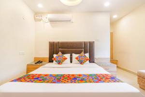a bedroom with a large white bed with colorful pillows at FabHotel Royal Aanandam in Gwalior