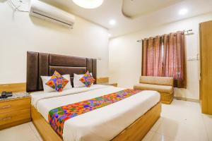 1 dormitorio con 1 cama grande y 1 silla en FabHotel Royal Aanandam, en Gwalior