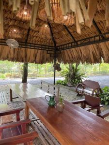 a wooden table and chairs under a straw umbrella at Giang House in Hòa Bình