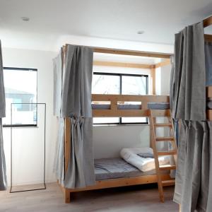 Etagenbett in einem Zimmer mit Fenster in der Unterkunft Matoi Hostel & Bar in Takasaki