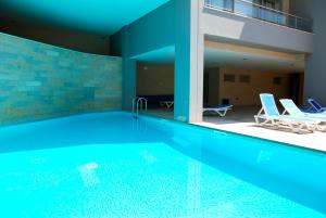 een zwembad met 2 stoelen en een gebouw bij Whale - Apartment with Wi-Fi and heated pool in São Martinho do Porto