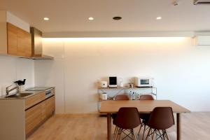 a kitchen with a wooden table and chairs at Matoi Hostel & Bar in Takasaki