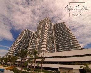 two tall buildings with palm trees in front of them at Stefan Staycation @ Azure North in San Fernando