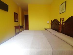 a bedroom with a large white bed in a yellow wall at Hotel Las Palmeras Celorio in Llanes