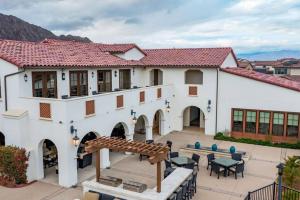 a large white house with a patio and tables at Near Coachella and Stagecoach Palm Springs , PGA resort Villa ,Golf, community pool, gym in La Quinta