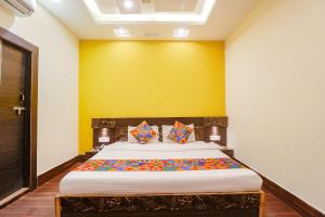 a bedroom with a bed with a yellow wall at FabExpress Ambika Dx in Gwalior