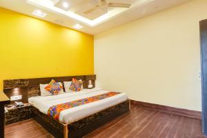 una camera con un letto con una parete gialla di FabExpress Ambika Dx a Gwalior