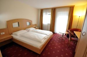 a bedroom with a bed and a desk and a chair at Cityhotel Tallero in Bressanone