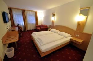 Habitación de hotel con cama y silla en Cityhotel Tallero en Bressanone