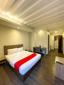 una camera da letto con un grande letto bianco con una coperta rossa di Airo Hotel Manila a Manila