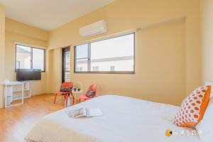 a bedroom with a bed and a tv and two chairs at 東居民宿 in Shih-san-fen