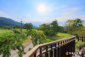 a wooden balcony with a view of a field at 東居民宿 in Shih-san-fen