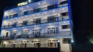un edificio blanco con balcones y luces. en Hotel Sunshine Dharamshala, en Dharamshala
