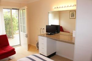 a room with a desk with a television and a mirror at Leura Fairways East in Leura