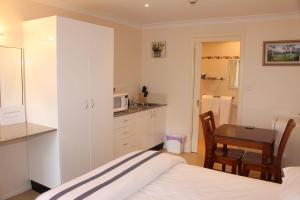 a bedroom with a bed and a kitchen with a table at Leura Fairways East in Leura