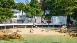 un groupe de personnes debout sur une plage de sable dans l'établissement Casa De Lipe, à Koh Lipe