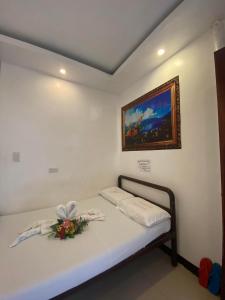 WJV INN Bankal في Bankal: سرير في غرفة مع لوحة على الحائط