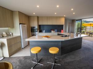 a kitchen with a large island with two bar stools at Number One Bach - Kaiteriteri Holiday Home in Kaiteriteri