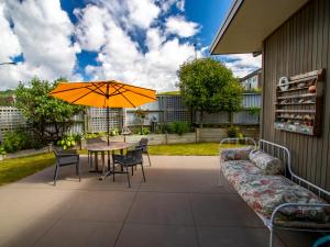 a patio with an umbrella and a table and chairs at Number One Bach - Kaiteriteri Holiday Home in Kaiteriteri
