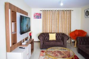uma sala de estar com um sofá e uma televisão em Havan Furnished Apartments-Milimani N8 em Nakuru