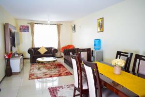 un soggiorno con tavolo, sedie e divano di Havan Furnished Apartments-Milimani N8 a Nakuru