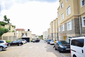 a city street with parked cars and buildings at Havan Furnished Apartments-Milimani N8 in Nakuru