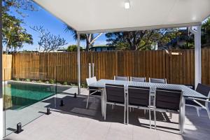 Un patio con mesa y sillas y una piscina. en 11 Ann Street, en Coolum Beach