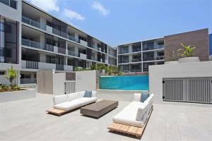 Cet appartement dispose d'une terrasse avec un mobilier blanc et d'une piscine. dans l'établissement Unit 406 Drift, à Coolum Beach