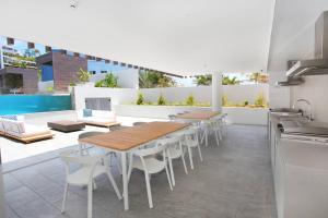une terrasse avec des tables et des chaises ainsi qu'une piscine dans l'établissement Unit 406 Drift, à Coolum Beach