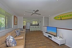 a living room with a couch and a flat screen tv at Red Door Beach House in Marcoola